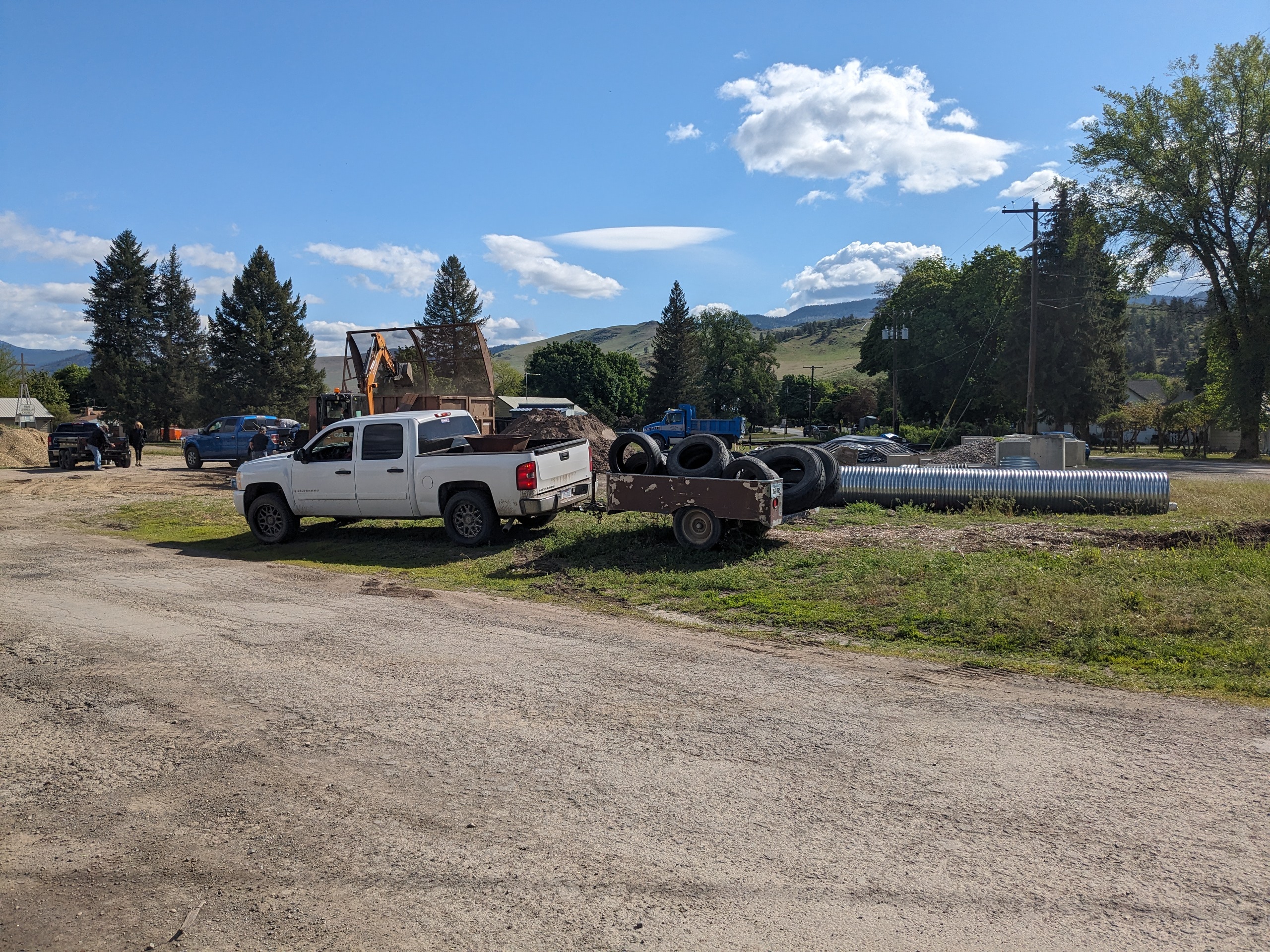 Excavator loading construction debris into a roll-off dumpster